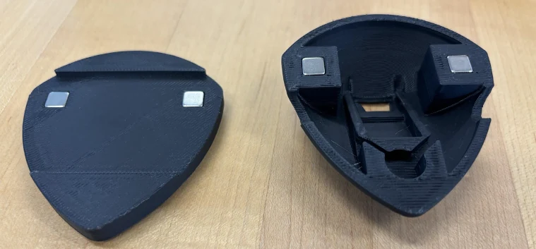 Two halves of the black 3D-printed SafeStride enclosure laid out on a table